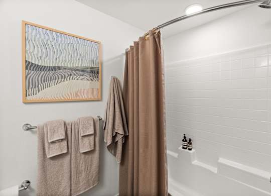 a bathroom with a shower and towels and a shower curtain