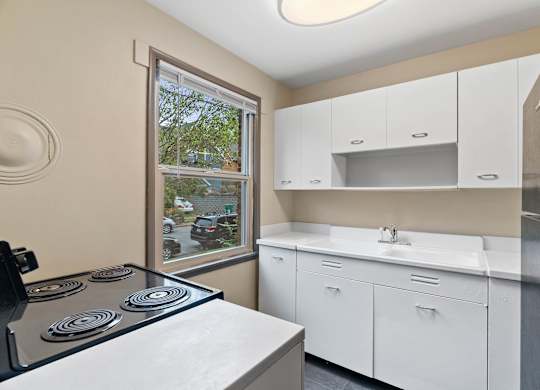 A kitchen with a stove top oven and white cabinets.