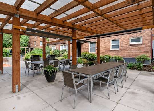 A wooden pergola with a table and chairs underneath.