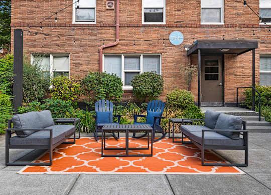 A patio with a table and chairs in front of a brick building.