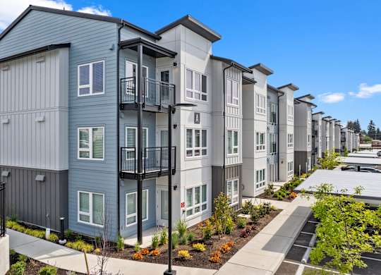A row of modern townhouses with balconies and landscaped gardens.