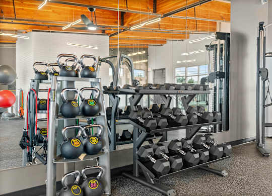 A gym with a variety of equipment including kettlebells and dumbbells.