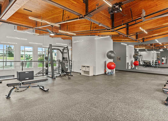 A gym with a wooden ceiling and a variety of exercise equipment.