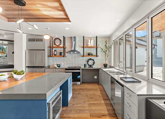 A modern kitchen with a wooden ceiling and a large window.