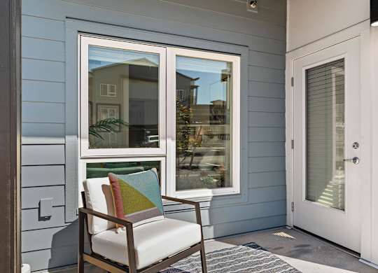 A chair with a cushion and a pillow is in front of a window.