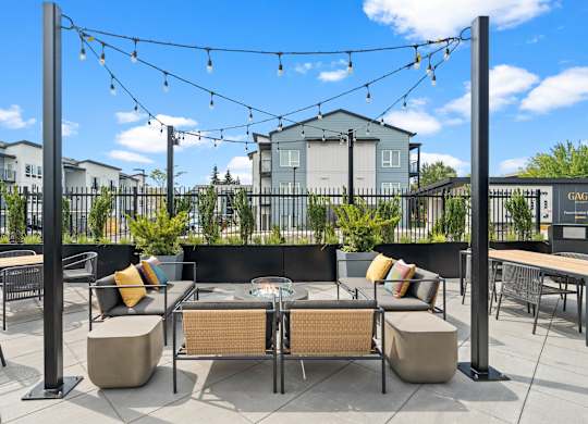 A patio with a table and chairs under a string of lights.