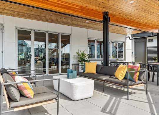 A patio with a couch, chair, and pillows.