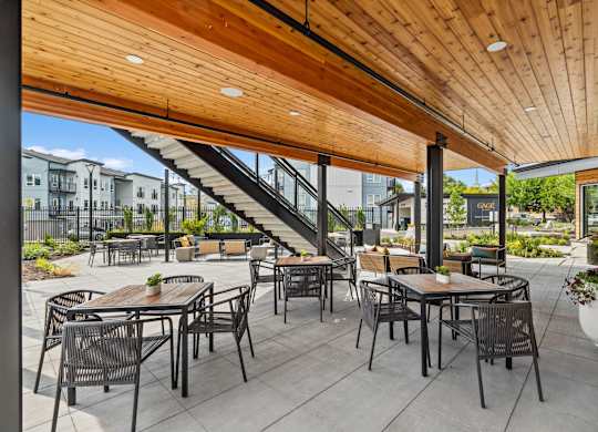 A patio with tables and chairs and a staircase.