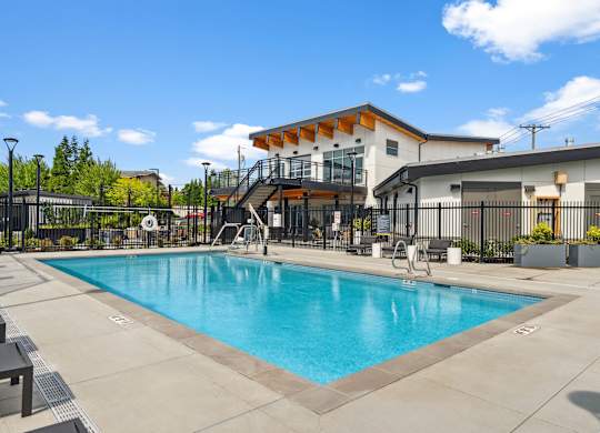A large swimming pool in front of a building with a black fence around it.