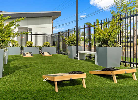 A backyard with a lawn, two benches, and a fence.