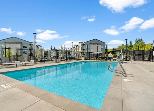 A large swimming pool surrounded by a fence and buildings.
