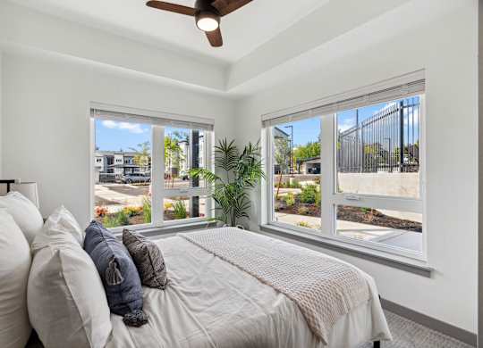 A bedroom with a bed, pillows, and a ceiling fan.