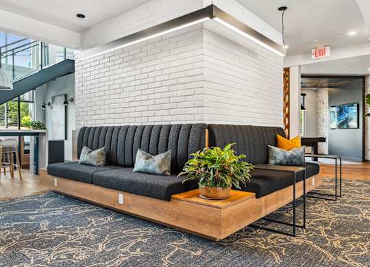 A black couch with a wooden table in front of a white brick wall.
