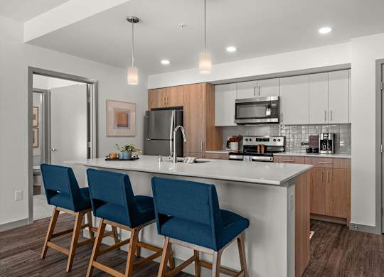 A kitchen with a white countertop and blue chairs.
