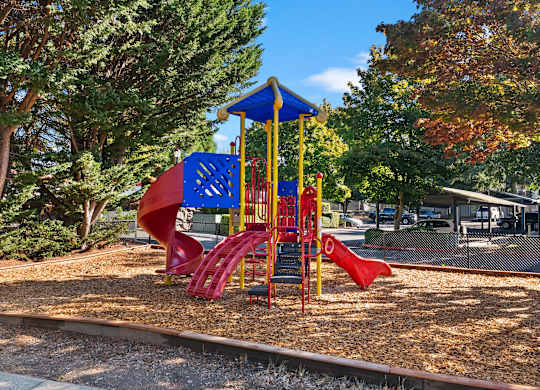A playground with a red slide and a blue and yellow structure.