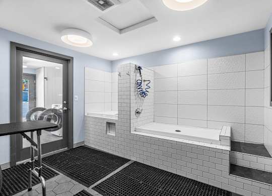 A bathroom with a white tiled shower area and a black mat on the floor.