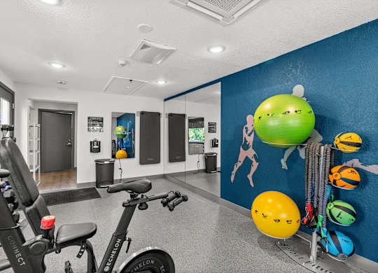 A gym room with exercise equipment and a blue wall with drawings of lemons.