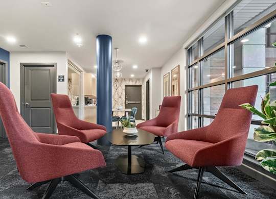 A room with red chairs and a round table.