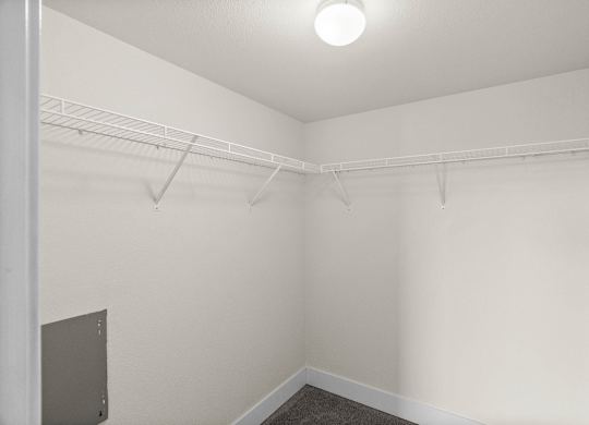 A white room with a shelf and a light on the ceiling.