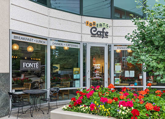 A restaurant named Fareatis Cafe with a signboard and flower bed in front.