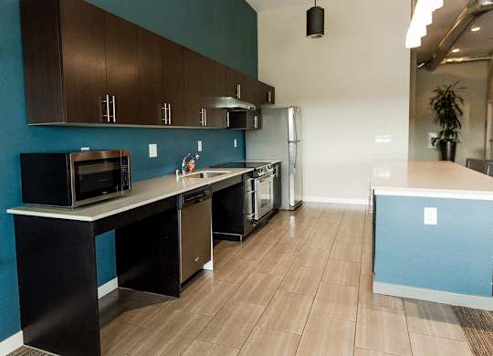 A kitchen with dark brown cabinets and a black microwave. at The Platform, Washington, 98032