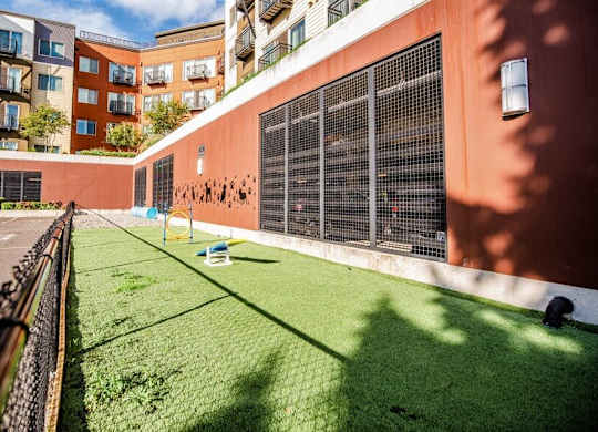 A small grassy area in front of a building with a fence on the left side. at The Platform, Washington, 98032