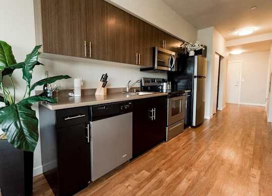 A kitchen with dark wood cabinets and stainless steel appliances. at The Platform, Kent, WA, 98032