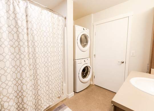 A white washing machine sits in a small laundry room. at The Platform, Kent, Washington