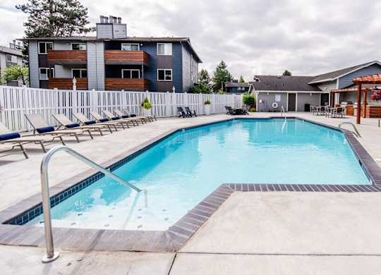 A swimming pool surrounded by a concrete floor and a metal ladder. at Vibe, Kent, WA, 98030