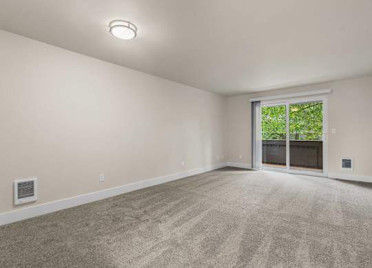 an empty living room with a large window and carpeting at Bellamy Park Apartments , Washington