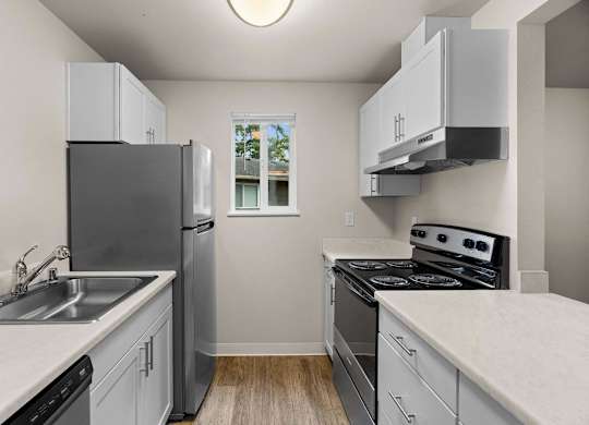 an empty kitchen with white cabinets and stainless steel appliances at Bellamy Park Apartments , Lakewood, CA