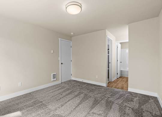 an empty living room with carpet and white walls at Bellamy Park Apartments , Lakewood