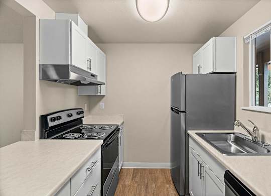 a kitchen with white cabinets and black appliances and a stainless steel refrigerator at Bellamy Park Apartments , Lakewood, Washington