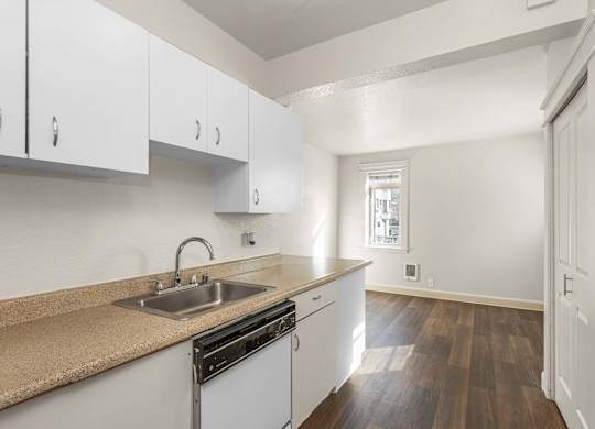 A kitchen with white cabinets and a brown countertop.