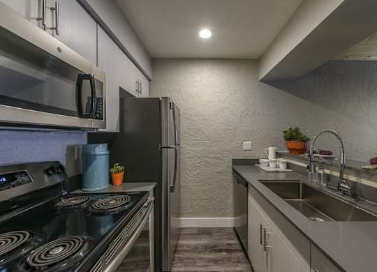 A modern kitchen with a stove, refrigerator, and sink.