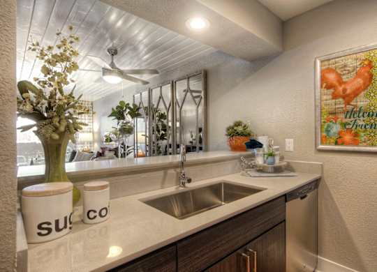 A kitchen with a white counter top and a painting on the wall.