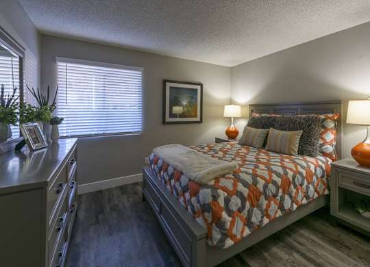 A bedroom with a bed, nightstand, and a painting on the wall.
