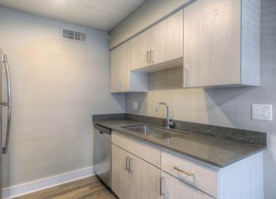 A kitchen with a refrigerator, sink, and cabinets.