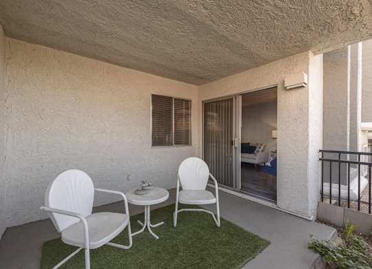 A patio with two chairs and a table.
