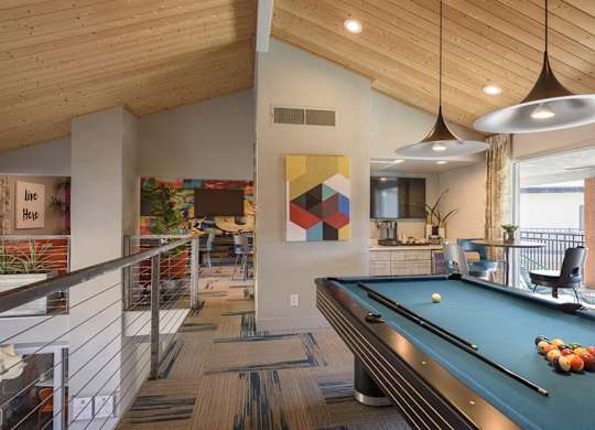 A pool table is in the middle of a room with a wooden ceiling.