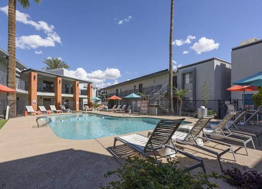 A pool surrounded by lounge chairs and umbrellas.