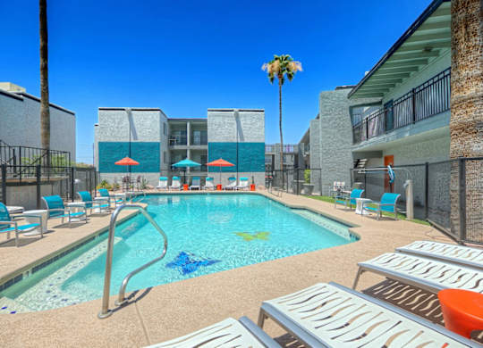 A pool with a slide and sun loungers.
