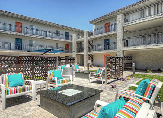 A patio area with a table and chairs in front of apartment buildings.