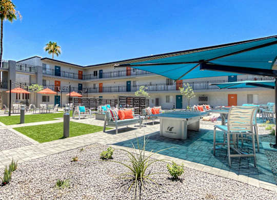 A pool area with a table and chairs under a shade sail.