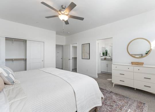 A bedroom with a large bed, a dresser, and a mirror.