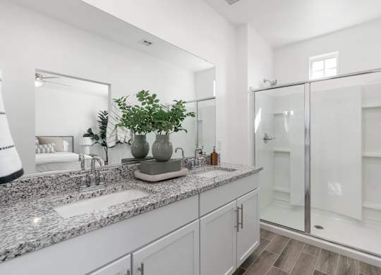 A bathroom with a marble countertop and a glass shower stall.