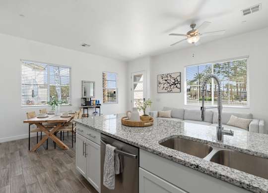A modern kitchen with a dining table and a ceiling fan.