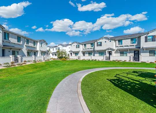A row of white houses with a curved walkway in the foreground.