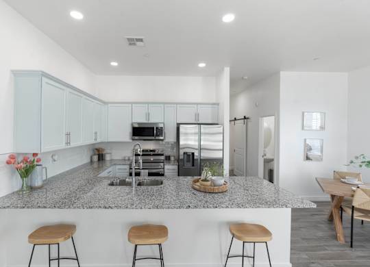 A kitchen with a granite countertop and stools.