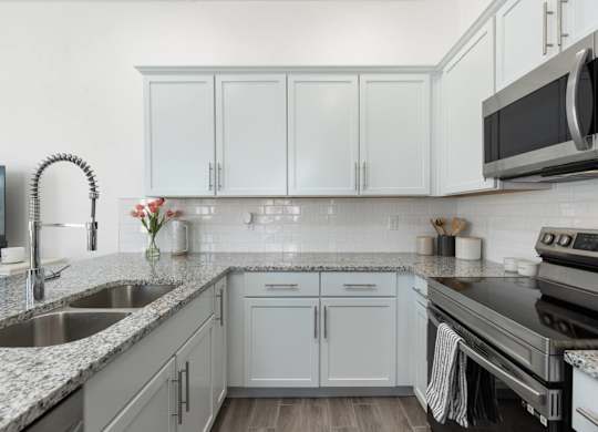 A kitchen with white cabinets and a black microwave.